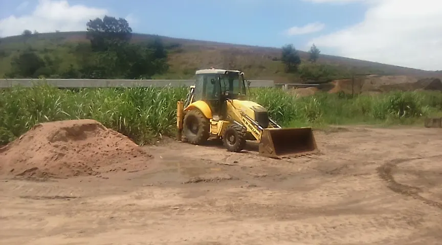 Sherry's New Holland TLB on a sand platform beside a cane field