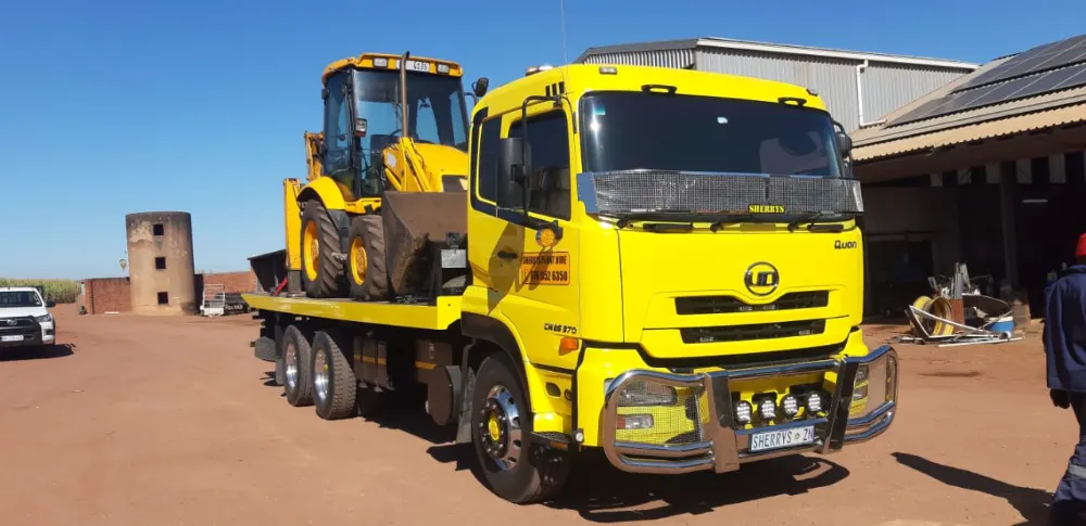 Sherry's yellow rollback loaded with a JCB TLB at a yard