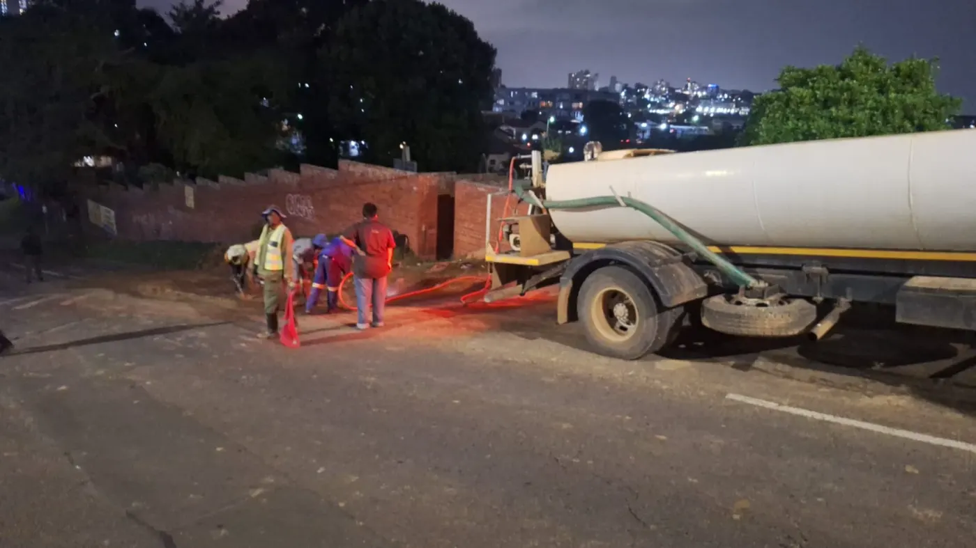 Sherry's water tanker on a night road job, the crew running a hose out behind it
