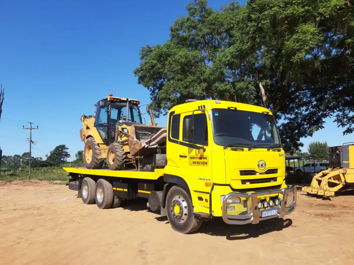 Sherry's yellow UD rollback loaded with a CAT TLB under a clear blue sky
